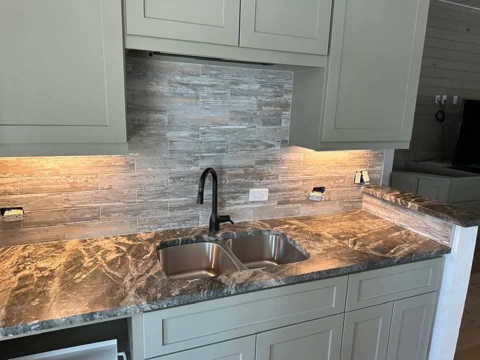 Kitchen with dark countertop and sage cabinetry